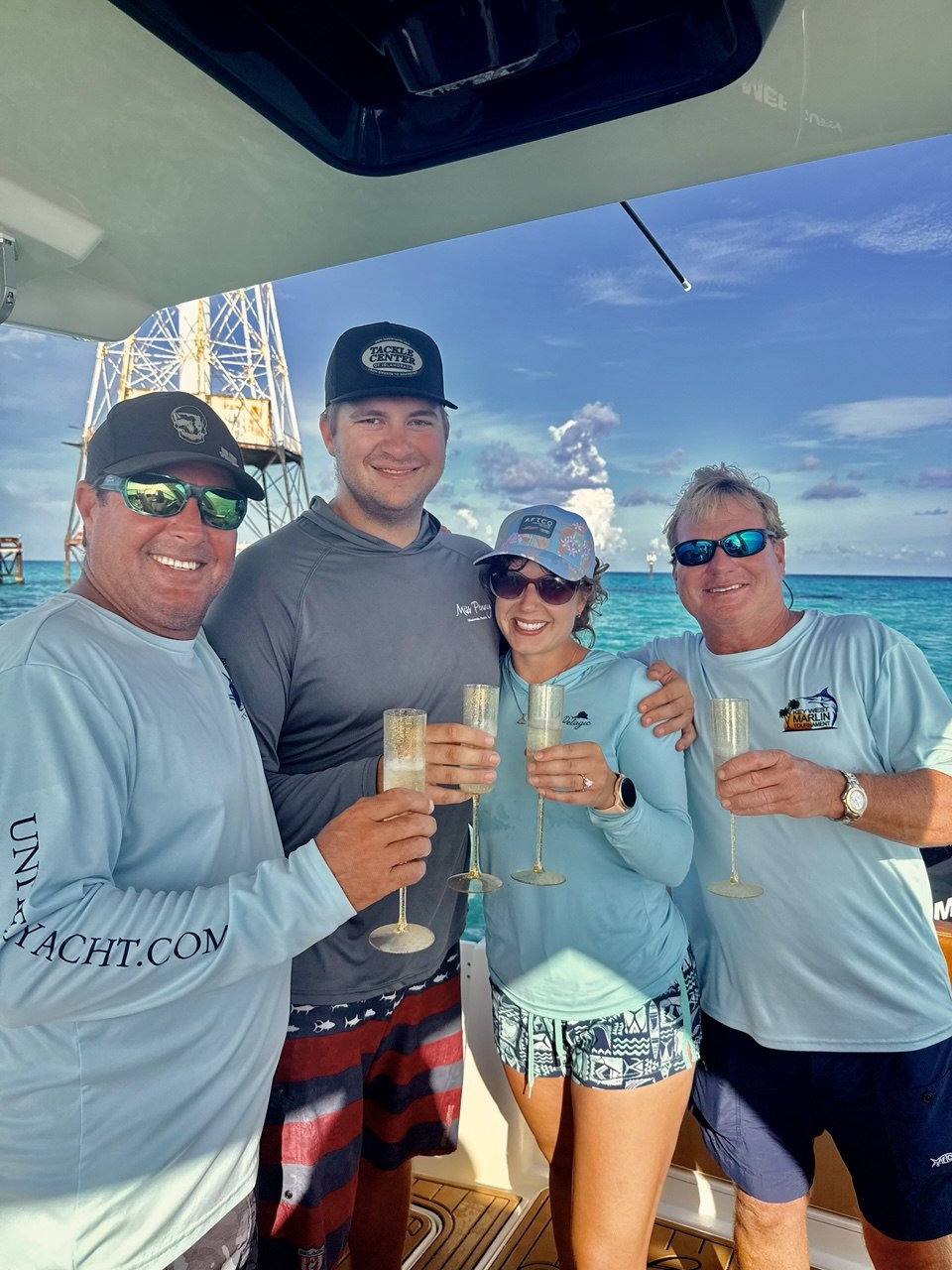 Four guests raising gold flutes aboard The Bougie Girl near Alligator Reef Lighthouse