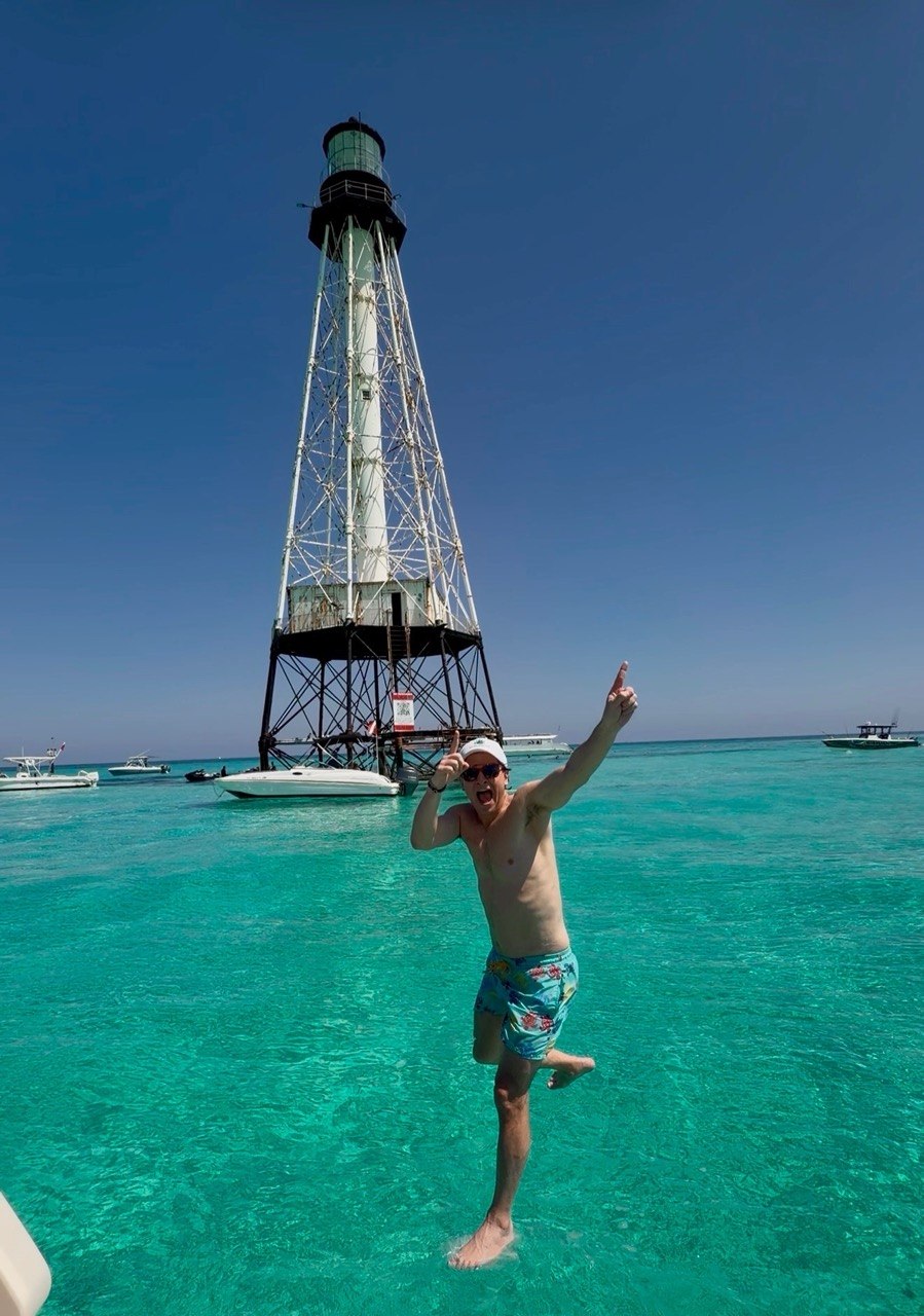 Guest jumping into turquoise water beside Alligator Reef Lighthouse